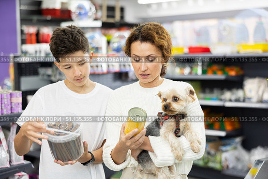 Woman with teenage son choosing food for Yorkshire terrier in pet store. Стоковое фото, фотограф Яков Филимонов / Фотобанк Лори