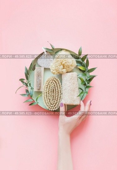 Women hand with eco friendly beauty and skin care bathroom accessories: natural sisal brush, wooden comb, soap, reusable make up removal pads. Zero waste. Top view. Natural and pastel colors. Стоковое фото, агентство Ingram Publishing / Фотобанк Лори