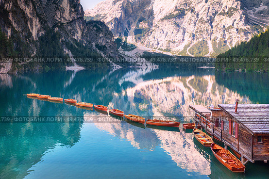Wooden boats in a row on summer morning at Lago di Braies (also known as Pragser Wildsee) in Dolomites Mountains, Sudtirol, Italy.. Wooden boats in a row on summer morning at Lago di Braies, Italy. Стоковое фото, агентство Ingram Publishing / Фотобанк Лори