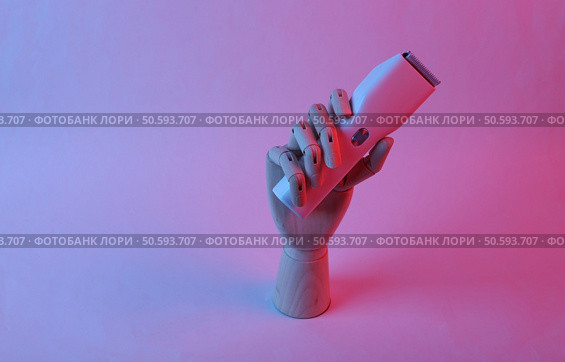 Wooden hand holding hair clipper in pink blue gradient neon light. Стоковое фото, агентство Ingram Publishing / Фотобанк Лори