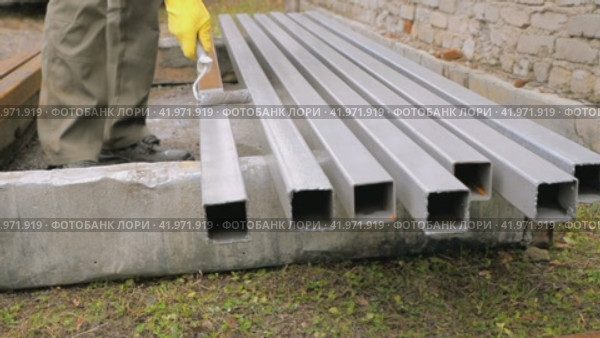 Work painter paints metal parts gray with a roller. Painting work in construction. Protection of metal square pipes from rust and corrosion. Стоковое видео, видеограф Дмитрий Кобзев / Фотобанк Лори