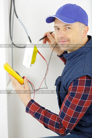 worker installing television cable internet wire in a room. Стоковое фото, агентство Ingram Publishing / Фотобанк Лори