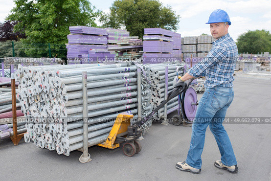 Worker moving pallet of scaffold poles. Стоковое фото, агентство Ingram Publishing / Фотобанк Лори