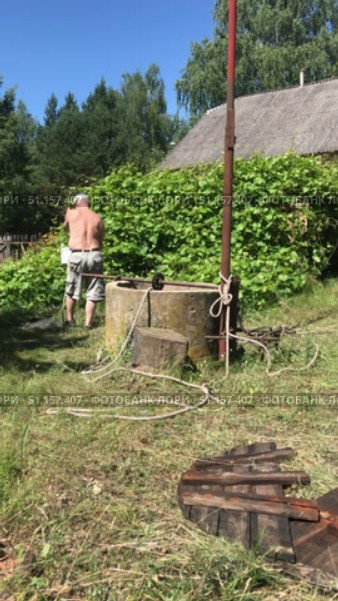 Workers are cleaning a mine shaft well. A man pulls out a bucket of dirty water from the well. Vertical video. Стоковое видео, видеограф Vadzim Yakubovich / Фотобанк Лори