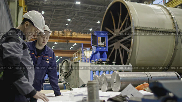 Workers with drawings on factory floor with machines. Стоковое фото, фотограф David Kashakhi / Фотобанк Лори
