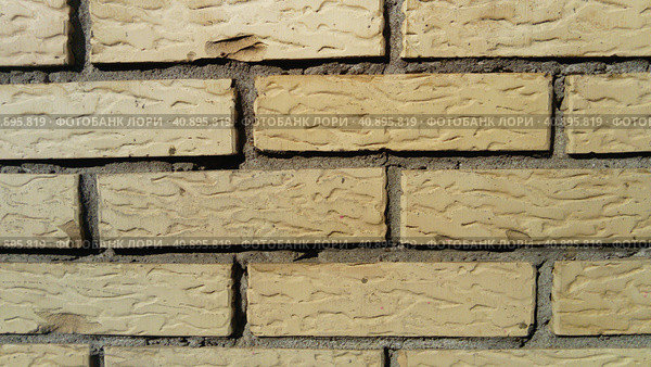 Yellow brick wall frontally. Ceramic brickwork or fence. Neatly and evenly laid brick. The light wall of the building, gray cement in the cracks. Sunny evening lighting. Стоковое фото, фотограф Юлия Петровская / Фотобанк Лори