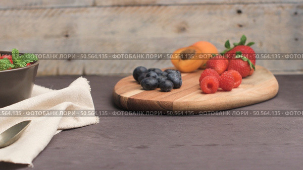 Yogurt with baked granola and berries in small bowl strawberries blueberries. Granola baked with nuts and honey for little sweetness. Slide from right. Стоковое фото, агентство Ingram Publishing / Фотобанк Лори