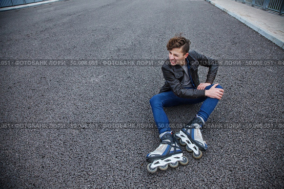 young attractive guy rubbing his knee, after falling on rollers. Стоковое фото, агентство Ingram Publishing / Фотобанк Лори