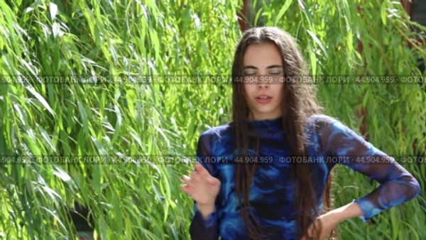 Young beautiful brunette girl posing in willow leaves. Стоковое видео, видеограф Андрей Аркуша / Фотобанк Лори