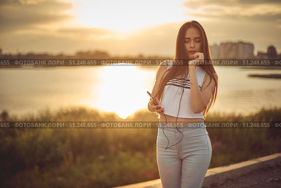 Young beautiful caucasian girl listening to music with smartphone walking in the city with headphones smiling - relax, youth, emancipation concept. Стоковое фото, фотограф Арзюков Вадим Николаевич / Фотобанк Лори