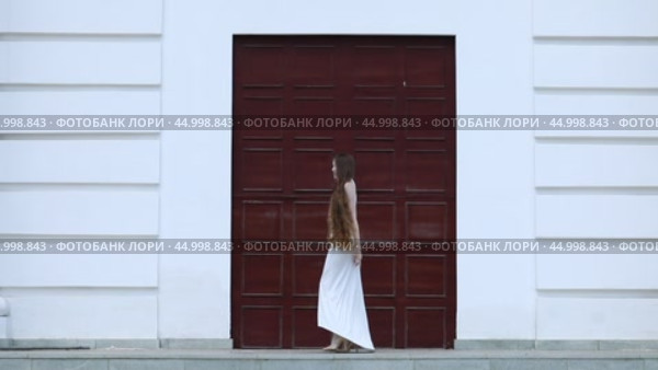 Young beautiful girl in a long white dress posing near a large gate. Стоковое видео, видеограф Андрей Аркуша / Фотобанк Лори