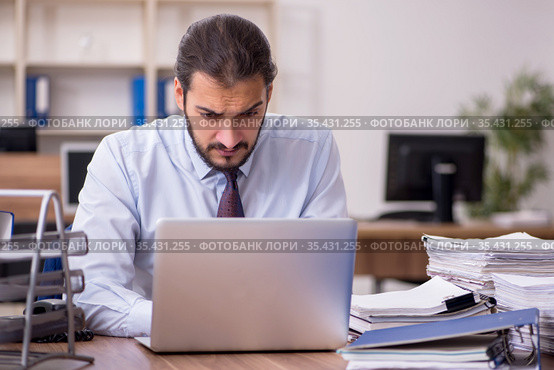 Young businessman employee unhappy with excessive work in the of. Стоковое фото, фотограф Elnur / Фотобанк Лори