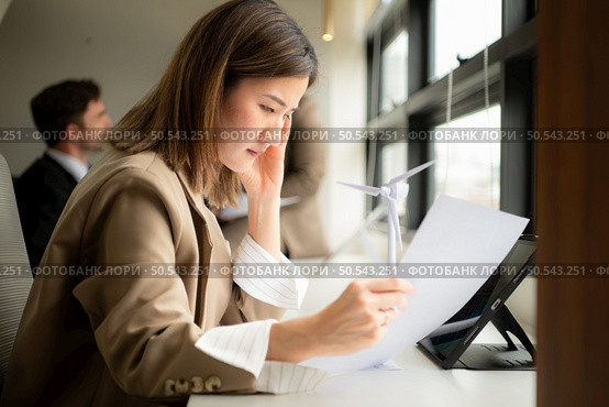 Young businesswoman and diverse group of business people working together in office, Brainstorming on how to use natural energy from wind and sunlight to offer customers. Стоковое фото, агентство Ingram Publishing / Фотобанк Лори