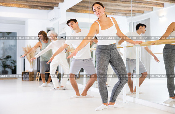 Young concentrated woman rehearsing ballet dance with other dancers in training room. Стоковое фото, фотограф Яков Филимонов / Фотобанк Лори