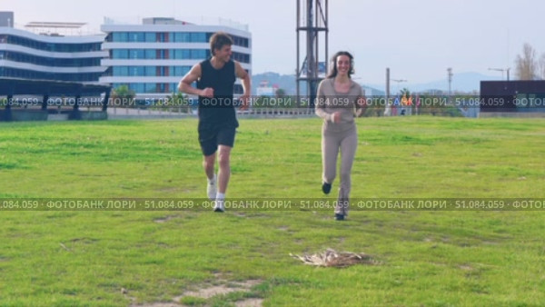 Young couple jogging together on palm-lined path enjoying outdoor exercise. Стоковое видео, видеограф Raquel Corcoles Mendez / Фотобанк Лори