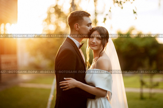 young couple the groom in a black suit and the bride in a white short dress on a walk in the village. Стоковое фото, агентство Ingram Publishing / Фотобанк Лори