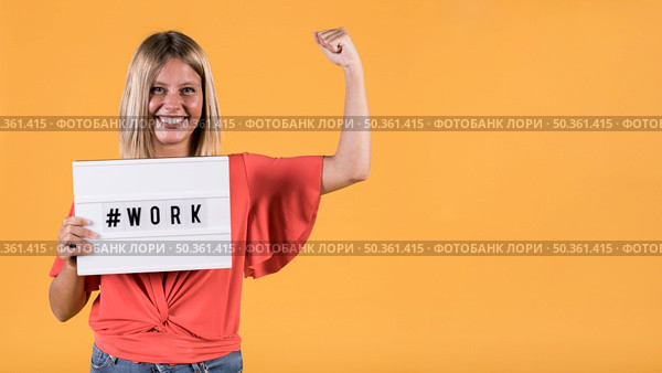 young deaf woman holding light box with hash tag work text flexing muscle yellow backdrop. Стоковое фото, агентство Ingram Publishing / Фотобанк Лори