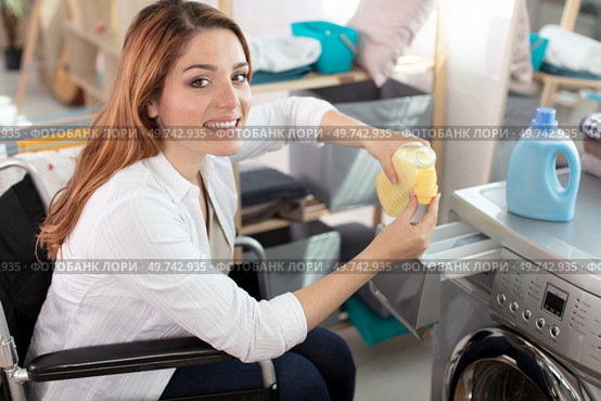 young disabled woman on wheelchair using washing machine. Стоковое фото, агентство Ingram Publishing / Фотобанк Лори