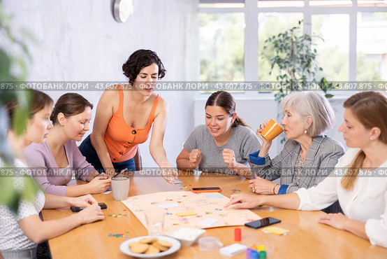 Young female moderator throws stones and determines order of parties in board game. Стоковое фото, фотограф Яков Филимонов / Фотобанк Лори