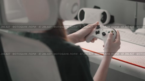 Young gamer immersed in gameplay, holding controller with high-tech computer setup. Close-up view highlights joystick, keyboard, and gaming accessories, showcasing virtual reality and technology. Стоковое видео, видеограф Енваев Андрей / Фотобанк Лори
