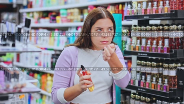 Young girl customer with tester, choosing perfume in cosmetic shop. Стоковое видео, видеограф Яков Филимонов / Фотобанк Лори