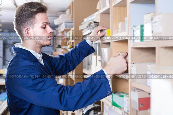 Young guy joiner searching for items in storage. Стоковое фото, фотограф Яков Филимонов / Фотобанк Лори