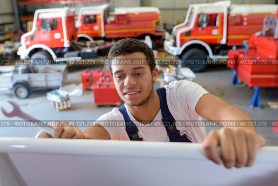 young handsome mechanic repairing motorbike in workshop. Стоковое фото, агентство Ingram Publishing / Фотобанк Лори