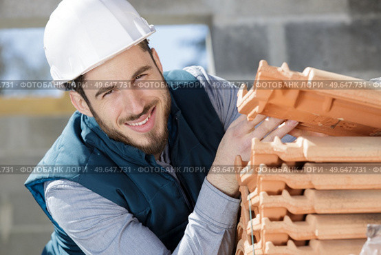 young happy man tiling on balcony ceramic tiles. Стоковое фото, агентство Ingram Publishing / Фотобанк Лори
