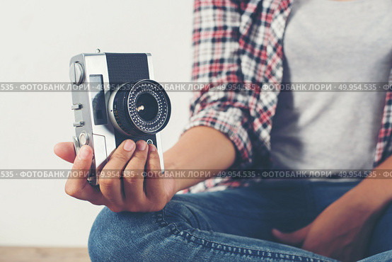 Young hipster photographer hand holding retro camera sitting on . Young hipster photographer hand holding retro camera sitting on wooden floor. Стоковое фото, агентство Ingram Publishing / Фотобанк Лори