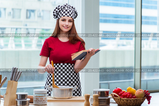 Young housewife referring to recipe book. Стоковое фото, фотограф Elnur / Фотобанк Лори