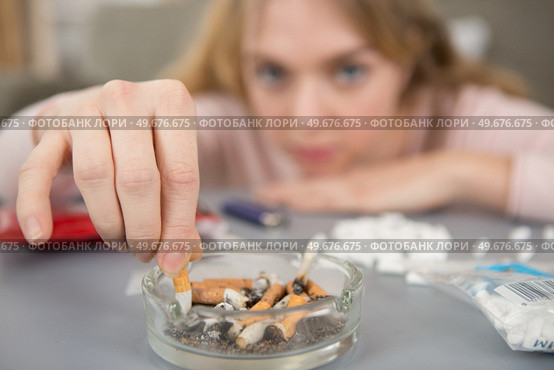 young lady stubbing a cigarette into an ashtray. Стоковое фото, агентство Ingram Publishing / Фотобанк Лори
