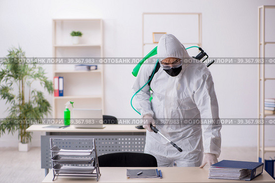Young male contractor disinfecting office during pandemic. Стоковое фото, фотограф Elnur / Фотобанк Лори