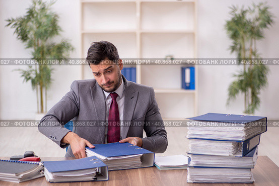 Young male employee and too much work in the office. Стоковое фото, фотограф Elnur / Фотобанк Лори