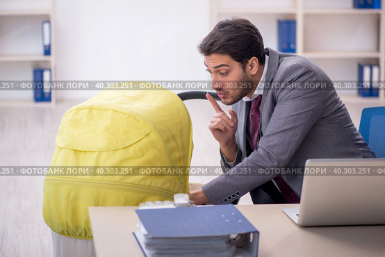 Young male employee looking after newborn at workplace. Стоковое фото, фотограф Elnur / Фотобанк Лори