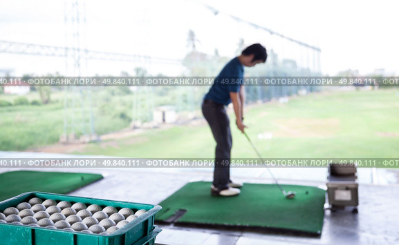 Young male golfer practicing his drive (Selective Focus at Golf ball tray) Стоковое фото, агентство Ingram Publishing / Фотобанк Лори