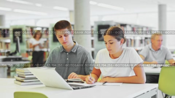 Young male librarian explaining information for casual female while she is using laptop in the library. Стоковое видео, видеограф Яков Филимонов / Фотобанк Лори