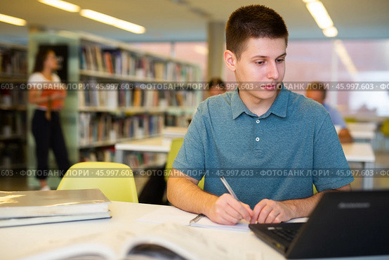 Young male student studying with a laptop in the library. Стоковое фото, фотограф Яков Филимонов / Фотобанк Лори