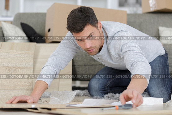 young man assembling furniture in new house. Стоковое фото, агентство Ingram Publishing / Фотобанк Лори
