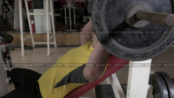Young man at the gym doing exercise chest press with rod. Стоковое видео, видеограф Данил Руденко / Фотобанк Лори