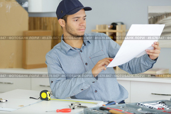 young man following instructions to assemble kitchen furniture. Стоковое фото, агентство Ingram Publishing / Фотобанк Лори
