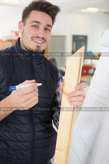 young man holding wood by a flipchart. Стоковое фото, агентство Ingram Publishing / Фотобанк Лори
