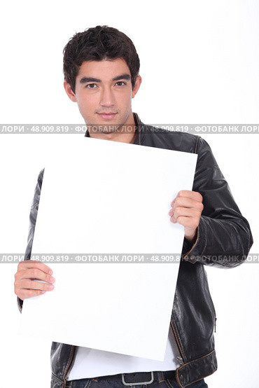Young man in a leather jacket holding a board left blank for your message. Стоковое фото, агентство Ingram Publishing / Фотобанк Лори