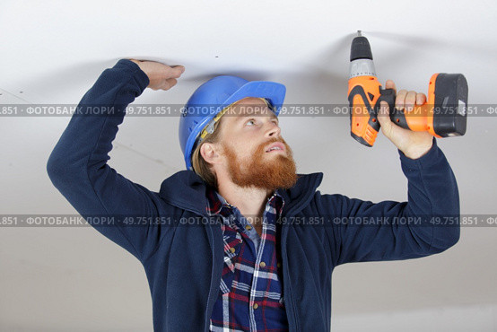 young man is drilling the ceiling. Стоковое фото, агентство Ingram Publishing / Фотобанк Лори