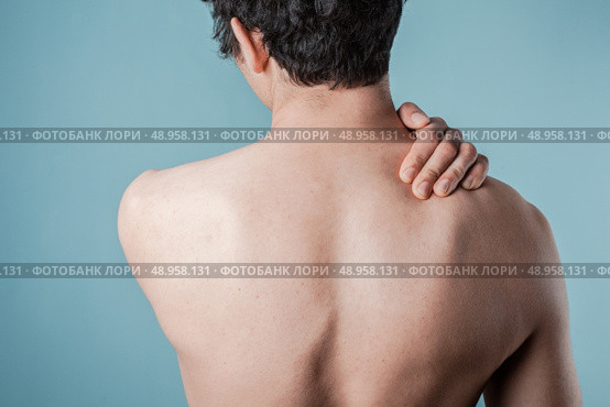 Young man is in pain and is massaging his sore neck. Стоковое фото, агентство Ingram Publishing / Фотобанк Лори
