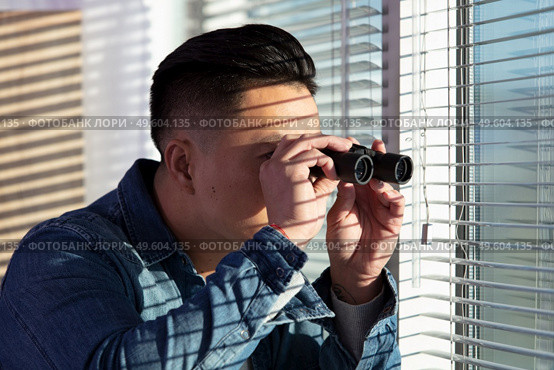young man looking through a glass window with binoculars. Стоковое фото, агентство Ingram Publishing / Фотобанк Лори