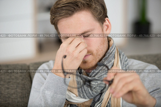 young man rubbing eye on white background annoying itch. Стоковое фото, агентство Ingram Publishing / Фотобанк Лори