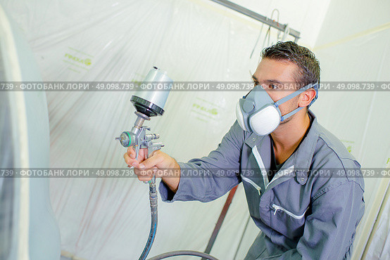 Young mechanic spray painting a car. Стоковое фото, агентство Ingram Publishing / Фотобанк Лори