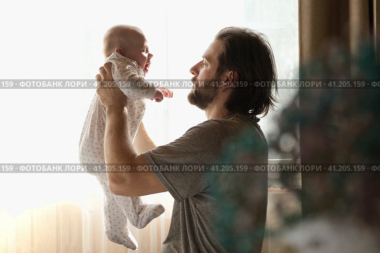 Young neo father is playing with his newborn baby in a nursery morning. Father's Day. Daddy holds in hands little Child and Plays with him. Concept of children, baby, parenthood, childhood, family. Стоковое фото, фотограф Марина Демидюк / Фотобанк Лори