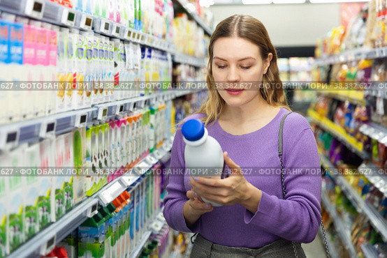 Young positive female customer choosing dairy products in supermarket. Стоковое фото, фотограф Яков Филимонов / Фотобанк Лори