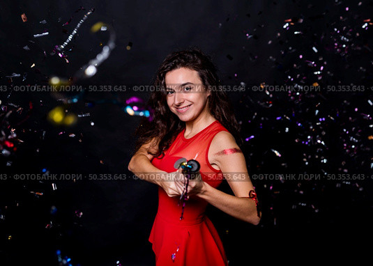 young smiling woman with popper tossing confetti. Стоковое фото, агентство Ingram Publishing / Фотобанк Лори